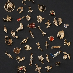 Detailed flat lay of assorted gold-plated titanium DIY charms with colorful enamel and zircons