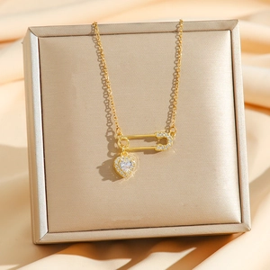 Safety pin pendant necklace with heart-shaped crystal charm in elegant gold finish