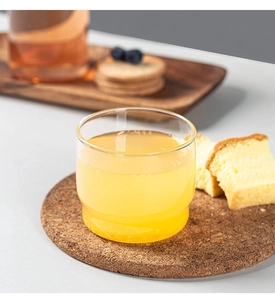 Stackable borosilicate glass cup detail on cork coaster with light juice and cake