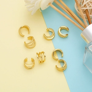 Detailed view of seven assorted golden ear cuffs with twisted and smooth textures
