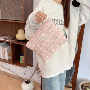 Detailed view of pink tweed makeup bag with woven texture and silver zipper slider