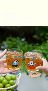 Détail de verres cartoon 300ml avec motifs panda et chien sur socle bleu clair pastel