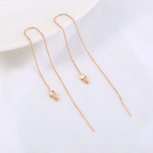 Detail of long golden fishbone threader earrings with sparkling zircon inlay
