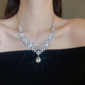 Close-up of sparkling silver V-shaped rhinestone necklace with pear-shaped pendant on neck