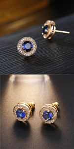 Macro shot of gold stud earrings with round blue gemstones and white zircon halo detail