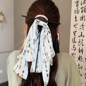 Detail of white satin hair ribbon with calligraphy and black tassel hairpin in a bun