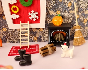 Dettaglio di un set miniatura natalizio con porta innevata, tappeto di benvenuto e accessori