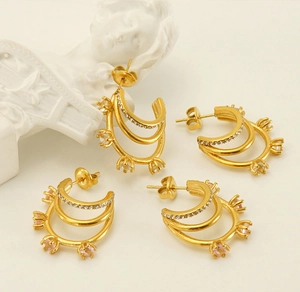 Détail de boucles d'oreilles dorées multicouches avec zircons roses et transparents
