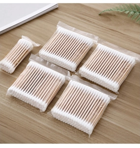 Detailed view of disposable dual-tip cotton swabs in clear pouches on a wooden table surface
