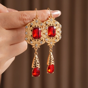 Macro detail of vintage baroque earrings with gold filigree and red teardrop gems