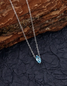 Detailed close-up of marquise-cut light blue zircon pendant on a silver chain necklace