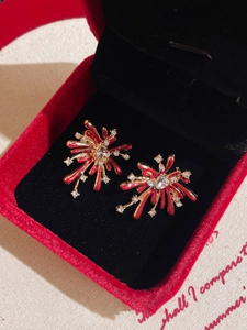 Close-up of sparkling red fireworks stud earrings with gold plating and rhinestones