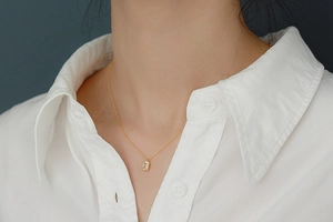 Close-up of a model wearing a gold S925 silver necklace with rectangular zircon pendant