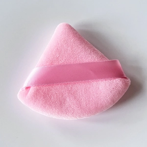 Detailed view of pink triangular velvet powder puff with soft ribbon handle for makeup