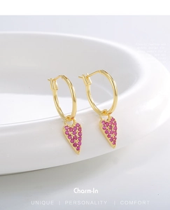 Close-up of gold hoop earrings featuring heart pendants set with pink cubic zirconia