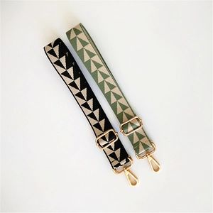 Detail of adjustable geometric woven bag straps with gold metal hardware in black and green