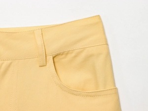 Détail du pantalon large en coton sergé jaune avec poches à double couture et texture du tissu