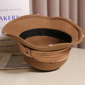 Detail of caramel wool felt hat featuring pearl accents and elegant bow ribbon decoration