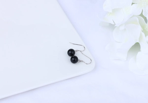Detailed view of natural black agate earrings with S925 silver hooks on white background