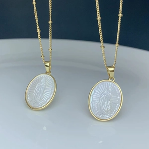 Detail of golden bead chain with oval white mother of pearl Virgin Mary pendant