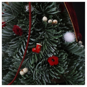 Close-up of mini red Christmas stocking ornament with gold stars on green pine branches