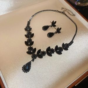 Macro shot of black gem wheat ear pendant necklace and earring set in luxury velvet box