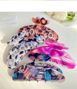Detailed macro view of four colorful floral hair claws with acetate finish and metal spring
