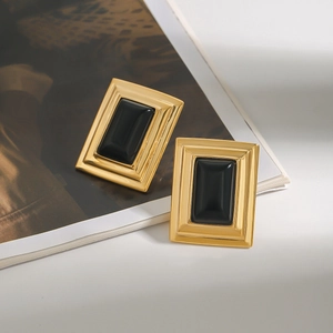 Detailed view of vintage gold rectangular earrings with black centers on a magazine