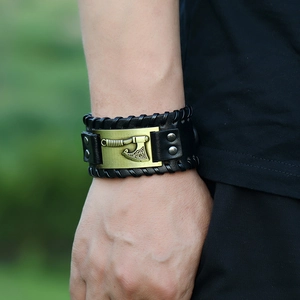 Close-up of black leather woven bracelet featuring a bronze Viking axe charm with Celtic patterns