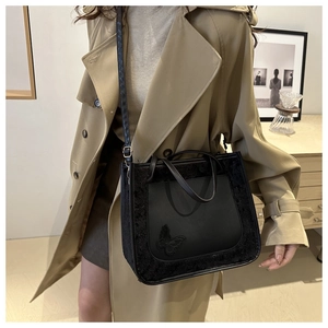 Détail du sac cabas noir avec texture peluche et broderie papillon sur la poche lisse