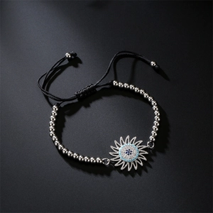 Detailed view of woven bracelet with evil eye sunflower charm and silver beads