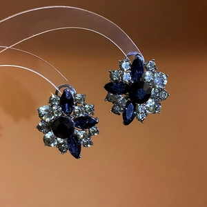 Macro shot of silver stud earrings with navy marquise stones and clear crystal petals