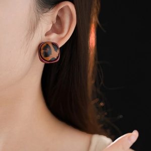 Gros plan d'une boucle d'oreille léopard avec bordure rectangulaire brune sur mannequin