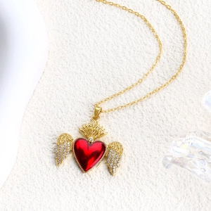 Close-up of gold heart pendant with red core, crown detail, and sparkling wings