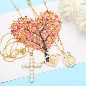 Detailed close-up of gold virgin mary medals and pearl cross pendants on thin beaded chains