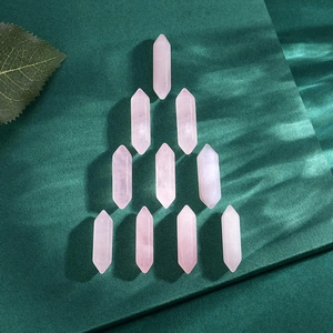 Macro shot of ten natural rose quartz hexagonal point pendants on a dark green fabric
