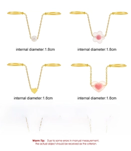 Detail of linked double rings with pearl, pink flower, and heart charms in gold plating