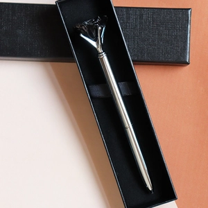 Detail view of a silver metal ballpoint pen with a black crystal top in a gift box