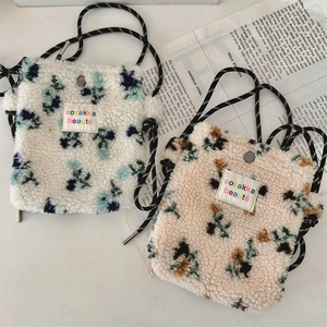 Detail of plush floral crossbody bags with embroidered labels and braided straps
