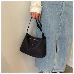 Minimalistische schwarze Nylon-Tragetasche von einem Model im Freizeit-Look getragen