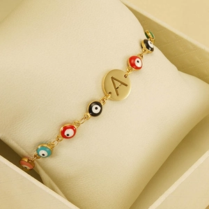 Macro detail of gold-plated evil eye bracelet with colorful beads and engraved letter A