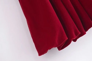 Détail du tissu en velours rouge foncé montrant la texture lisse et le drapé de la robe
