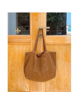 Detailed close-up of brown corduroy tote bag texture and front square pocket design
