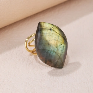 Detailed close-up of a gold multi-band ring featuring an iridescent raw labradorite stone
