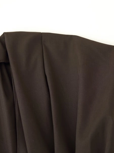 Detail shot of pleated dark brown dress fabric showing smooth texture and drape quality