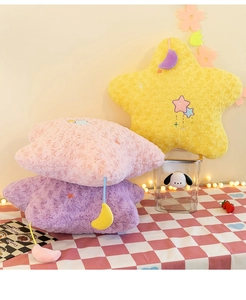 Close-up of star-shaped plush pillows in yellow, pink and purple with moon charms