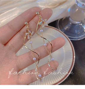 Detailed shot of gold long tassel star earrings featuring white pearls and star zircons