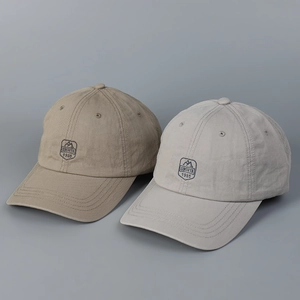 Close-up of embroidered mountain shield patch on khaki and grey cotton baseball caps