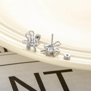 Polished silver metal bow stud earrings with secure screw back closure on neutral base