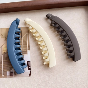 Detailed view of matte plastic banana hair clips in blue, cream, and dark grey tones